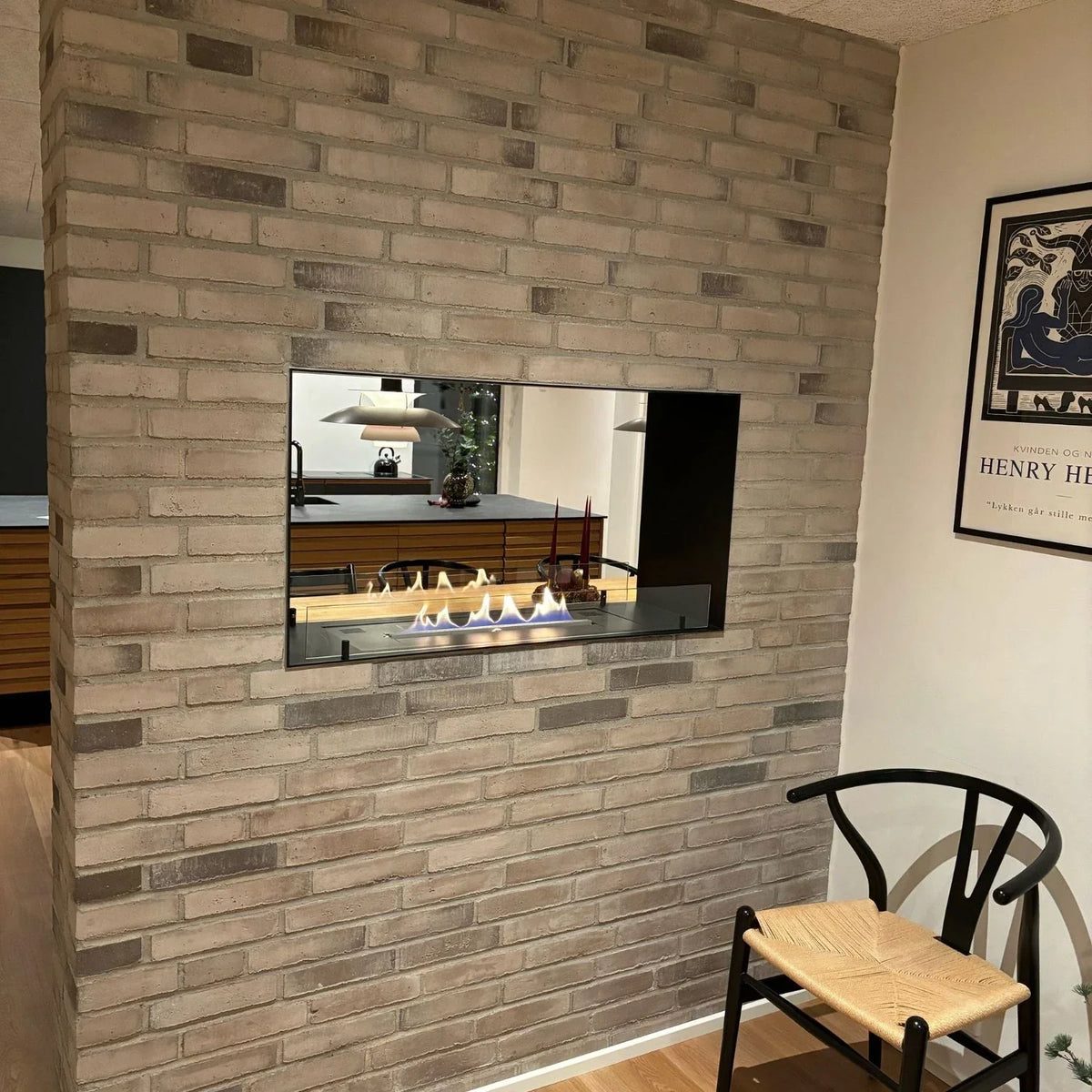 Foco Two 800 built into a grey brick partition wall, genuine customer installation photo, lit flame visible from both sides